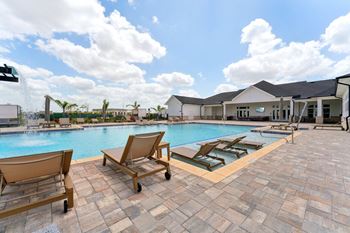 A pool with sun loungers and a building in the background.